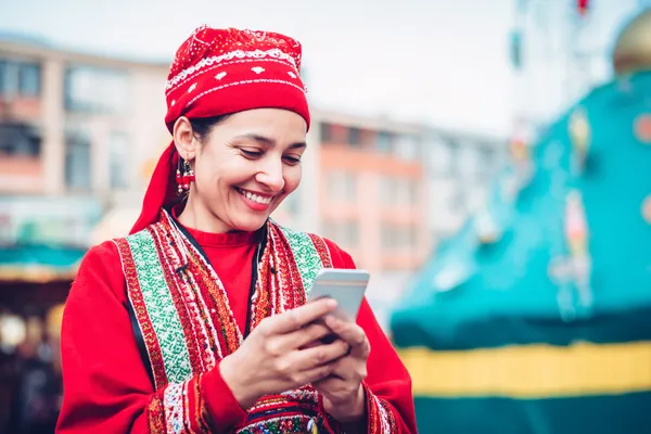 A young woman relaxing with her phone while dynamic casino elements float around her, illustrating the smooth mobile experience offered by the 100JLPH app.