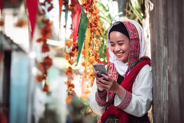 A player using their smartphone during a festive local event, representing 100JLPH’s fully mobile-friendly casino.